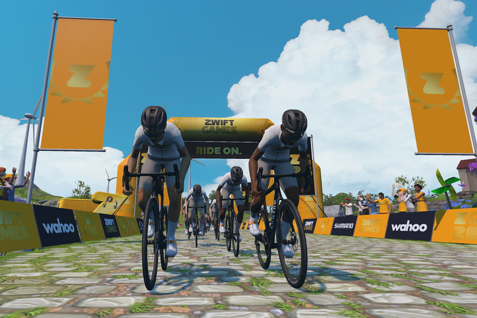 Screenshot der virtuellen Zwift-Welt: zwei Radfahrer von vorn fahren im Sprint durch einen Start-/Zielbogen