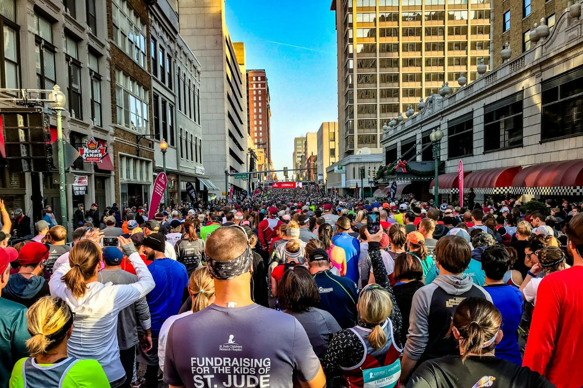 Eine große Gruppe an Marathonläufern in einer Stadt kurz vor dem Start von hinten fotografiert.