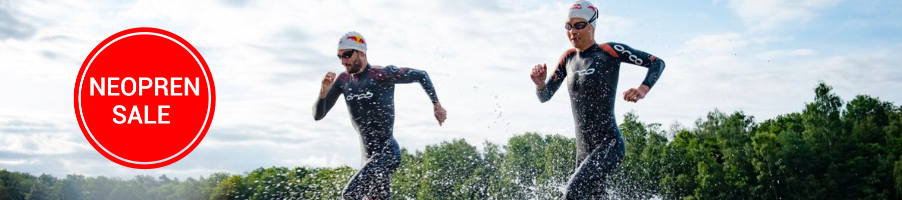 Zwei Triathleten laufen im Neoprenanzug dynamisch in einen See hinein