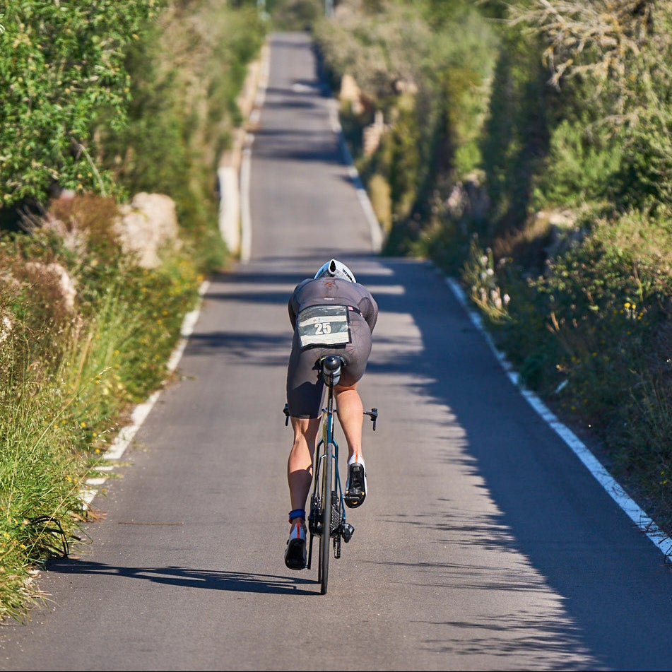 Ein Triathlet auf seinem Fahrrad von hinten fährt auf einer schmalen Straße durch das mallorcinische Hinterland
