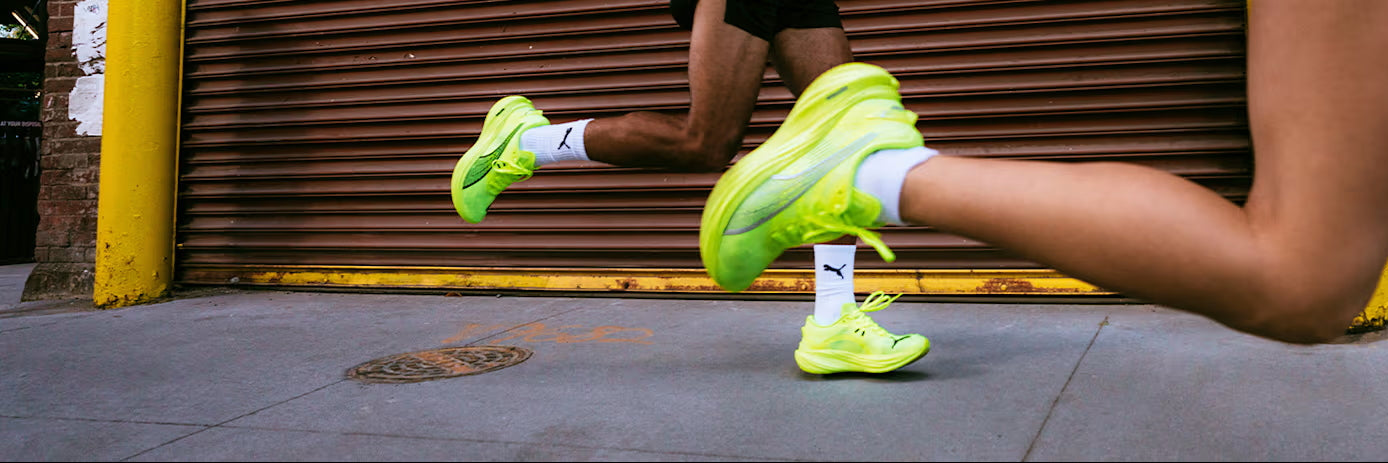 Zwei Läufer mit neongelben Puma Laufschuhen von der Seite, nur die Unterschenkel mit den Schuhen sind zu sehen